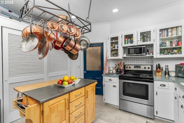 kitchen with decorative backsplash, light tile patterned floors, ornamental molding, appliances with stainless steel finishes, and white cabinetry