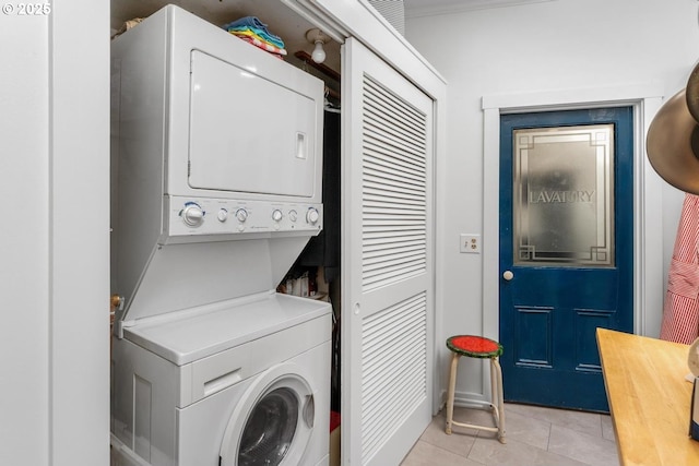 laundry room featuring light tile patterned floors and stacked washer / drying machine