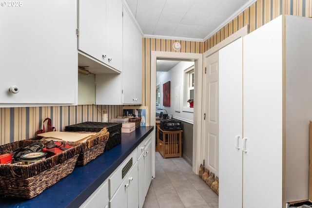 kitchen with white cabinets, crown molding, and light tile patterned flooring