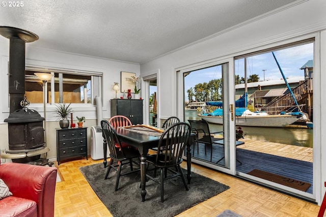 dining area featuring a wood stove, light parquet floors, and a textured ceiling