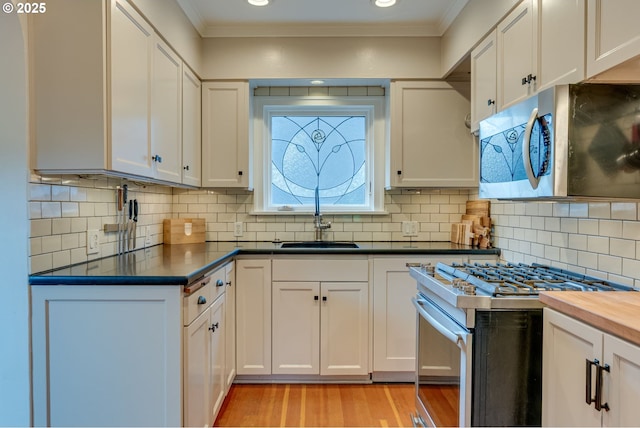 kitchen with stainless steel appliances, crown molding, light wood finished floors, white cabinetry, and a sink