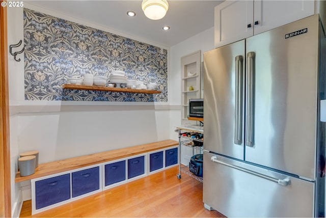 kitchen with high end refrigerator, open shelves, wood counters, blue cabinetry, and light wood-style flooring
