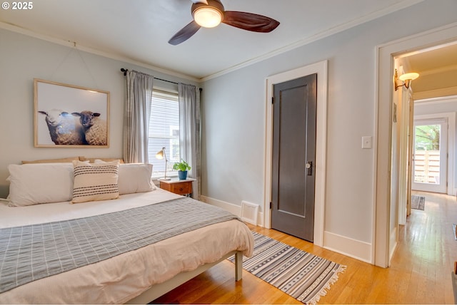bedroom with baseboards, crown molding, light wood-type flooring, and ceiling fan
