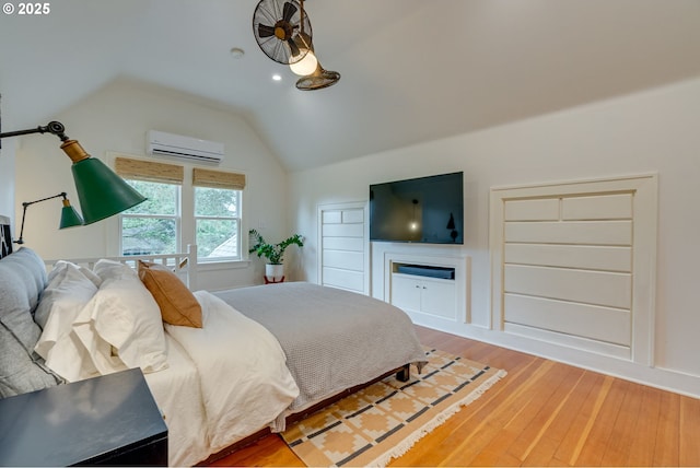 bedroom featuring lofted ceiling, a wall unit AC, light wood-style flooring, and recessed lighting