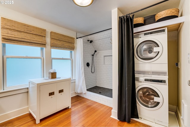 washroom featuring stacked washer / dryer, light wood-type flooring, and baseboards