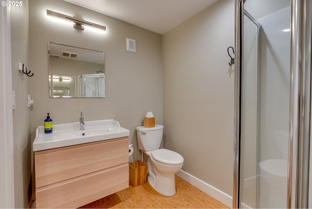 full bath featuring toilet, wood finished floors, vanity, a shower with shower door, and baseboards