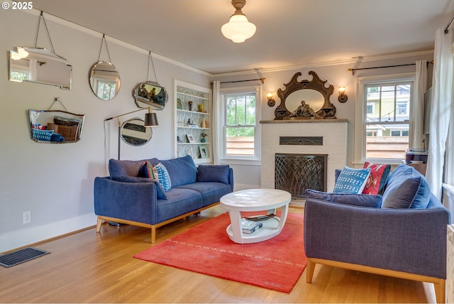 living room with wood finished floors, crown molding, plenty of natural light, a fireplace, and baseboards
