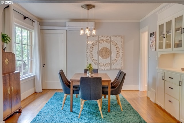 dining room with a wall mounted AC, light wood finished floors, crown molding, and baseboards