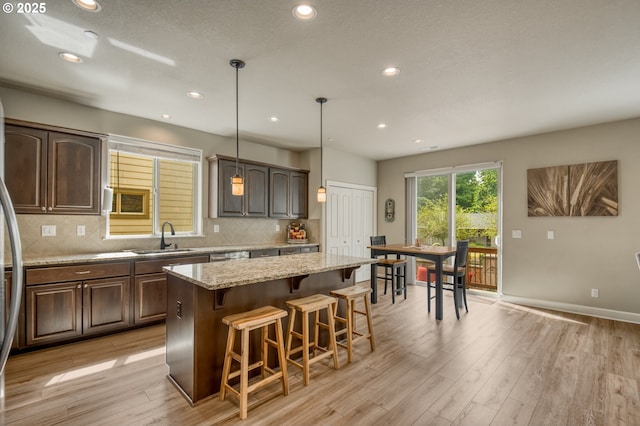 10380 SW Madrid Loop, Wilsonville, OR 97070 - kitchen with a kitchen island, light wood-type flooring, a kitchen bar, tasteful backsplash, and recessed lighting