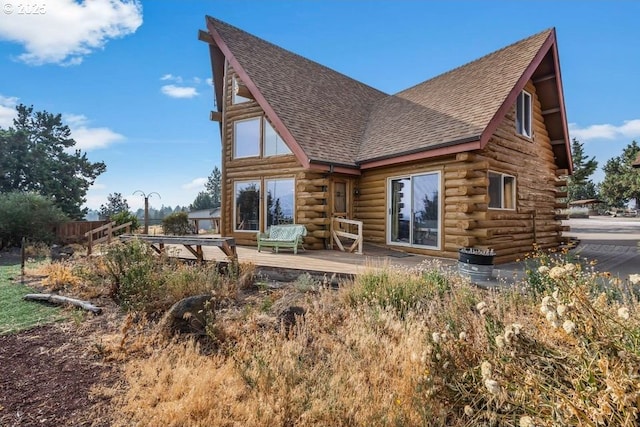 rear view of house with a deck, log exterior, and roof with shingles