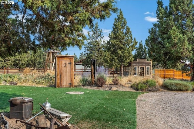 view of yard featuring a storage shed, an outbuilding, and fence