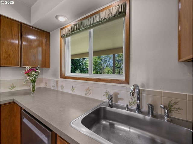 kitchen featuring a sink, stainless steel dishwasher, backsplash, and brown cabinetry
