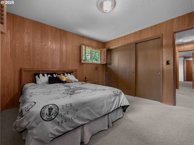 carpeted bedroom with a textured ceiling, wood walls, and a closet