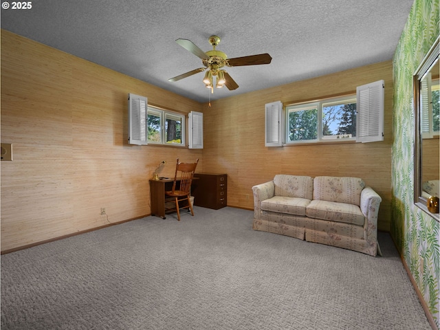 carpeted living area featuring a ceiling fan and a textured ceiling