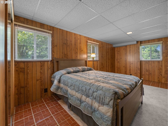 bedroom with wooden walls, brick patterned floor, and a paneled ceiling