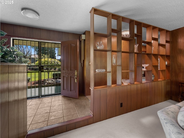 interior space with wooden walls, tile patterned floors, and a textured ceiling
