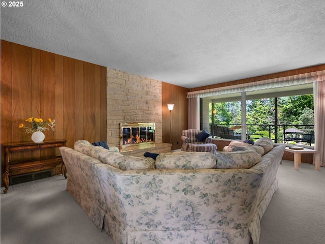 living area featuring a textured ceiling, wood walls, light colored carpet, and a stone fireplace