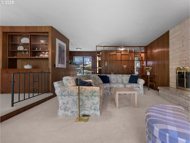 carpeted living area with a fireplace, wood walls, and a textured ceiling