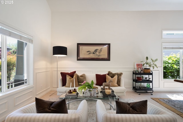 living room featuring carpet floors, a decorative wall, and a wainscoted wall