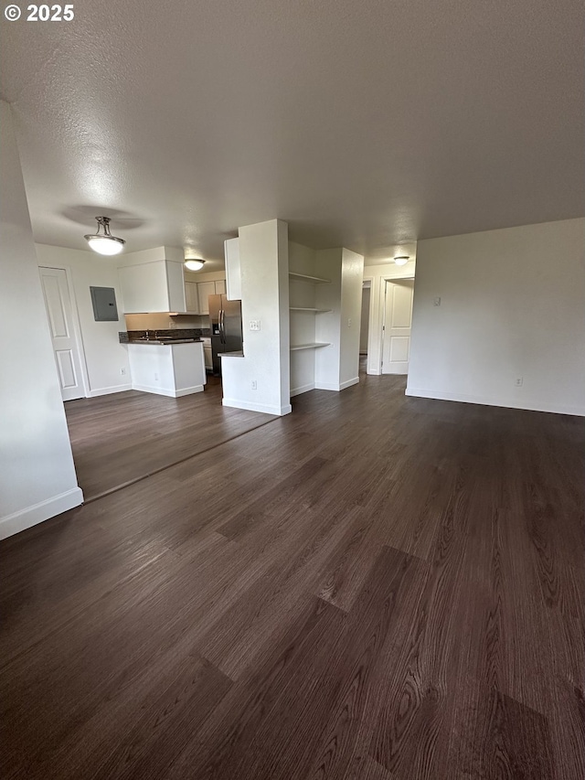 unfurnished living room with dark wood-type flooring and a textured ceiling