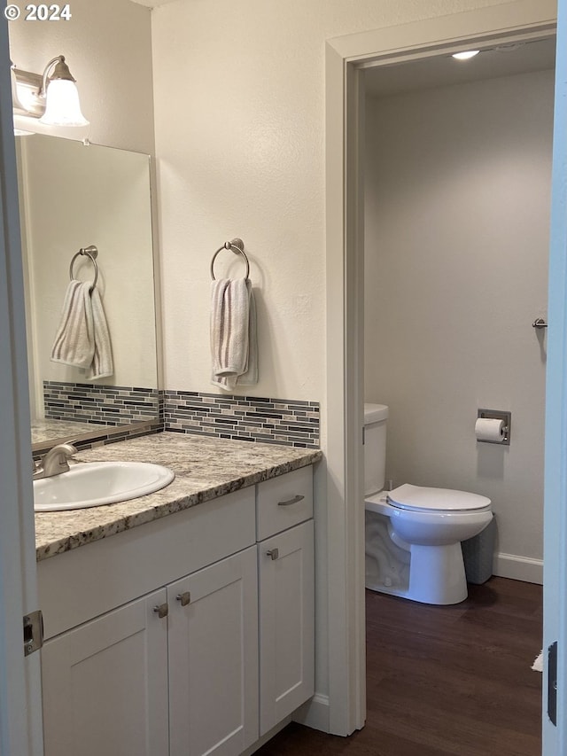 bathroom with vanity, decorative backsplash, wood-type flooring, and toilet