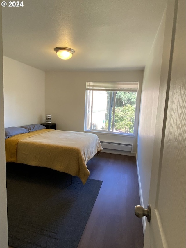 bedroom with baseboard heating and dark hardwood / wood-style flooring