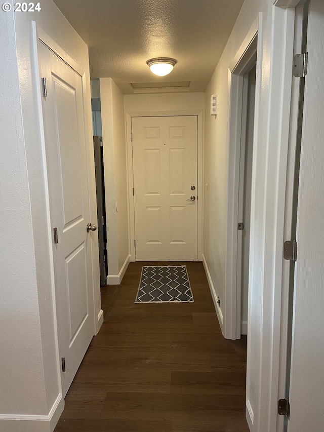 hallway with dark wood-type flooring and a textured ceiling