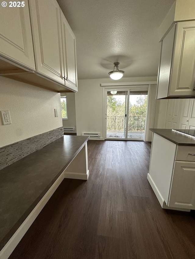 interior space with white cabinetry, dark hardwood / wood-style floors, a textured ceiling, and baseboard heating