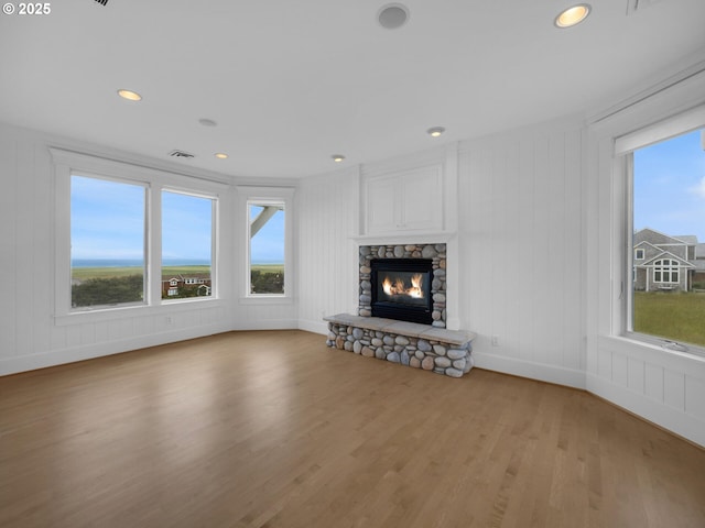 88902 Pinehurst Rd, Gearhart, OR 97138 - unfurnished living room with plenty of natural light, a decorative wall, light wood-style flooring, a fireplace, and baseboards