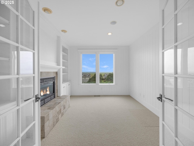 88902 Pinehurst Rd, Gearhart, OR 97138 - unfurnished living room featuring a tiled fireplace, carpet, built in shelves, recessed lighting, and french doors