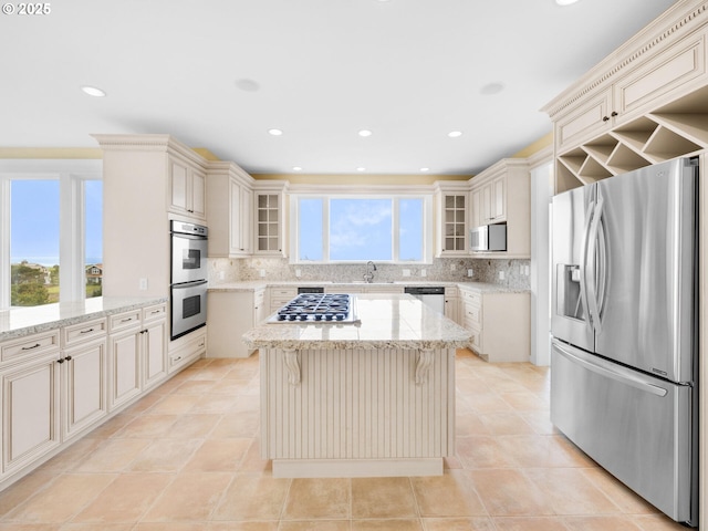 88902 Pinehurst Rd, Gearhart, OR 97138 - kitchen with stainless steel appliances, a sink, cream cabinetry, a center island, and tasteful backsplash