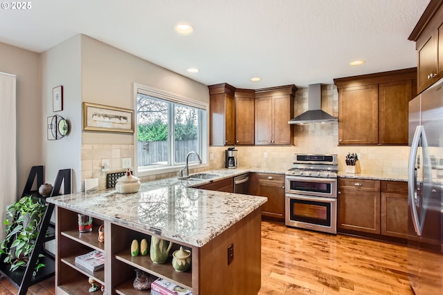 kitchen with wall chimney exhaust hood, light wood-type flooring, open shelves, a sink, and stainless steel appliances