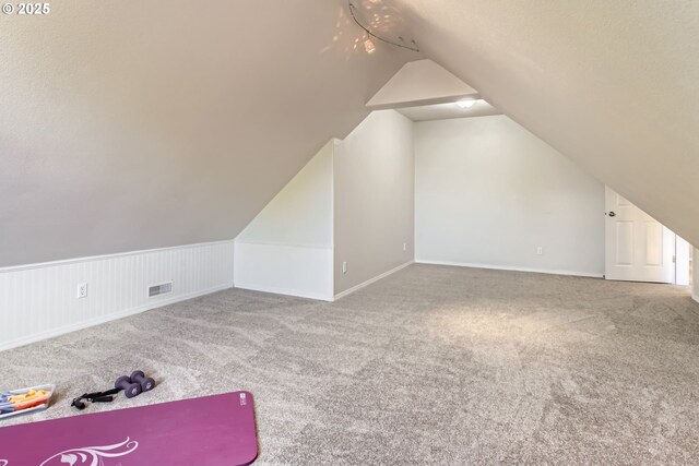 additional living space with carpet, visible vents, and lofted ceiling