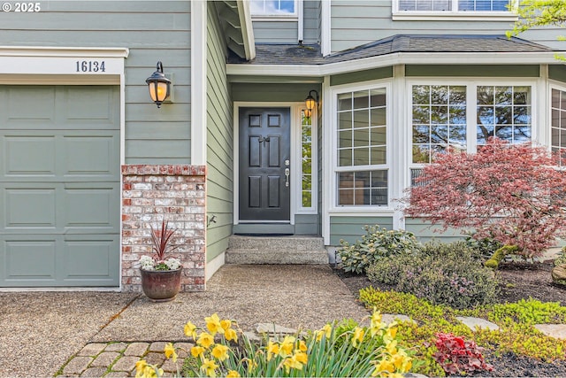 view of exterior entry featuring a shingled roof and a garage