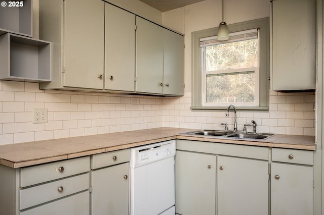 kitchen with pendant lighting, tile counters, sink, backsplash, and white dishwasher