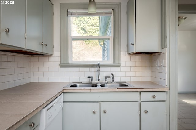 kitchen with dishwasher, sink, decorative light fixtures, tile countertops, and decorative backsplash