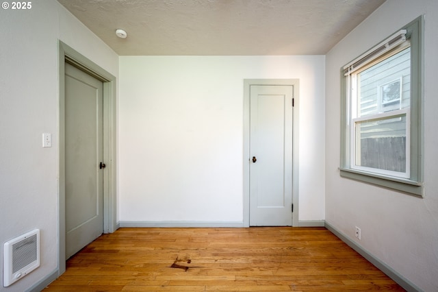 empty room featuring heating unit and light hardwood / wood-style floors