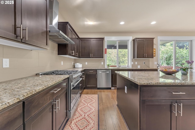 8070 SW 195th Ave, Beaverton, OR 97007 - kitchen featuring stainless steel appliances, wall chimney exhaust hood, dark brown cabinetry, recessed lighting, and light wood-style floors