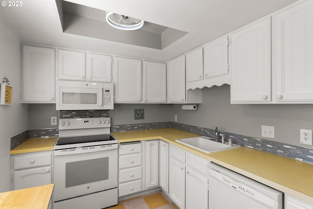 kitchen with white appliances, a sink, white cabinetry, and light countertops