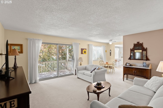 living room with a textured ceiling, healthy amount of natural light, light colored carpet, and a ceiling fan