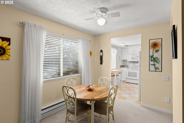 dining area featuring a baseboard heating unit, ceiling fan, baseboards, light floors, and a textured ceiling