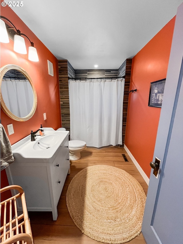 bathroom with curtained shower, wood finished floors, visible vents, toilet, and vanity