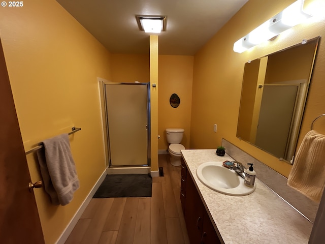 full bath featuring toilet, a stall shower, baseboards, wood finished floors, and vanity