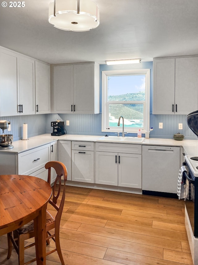 kitchen with a sink, range with electric cooktop, light wood-type flooring, white cabinetry, and dishwasher