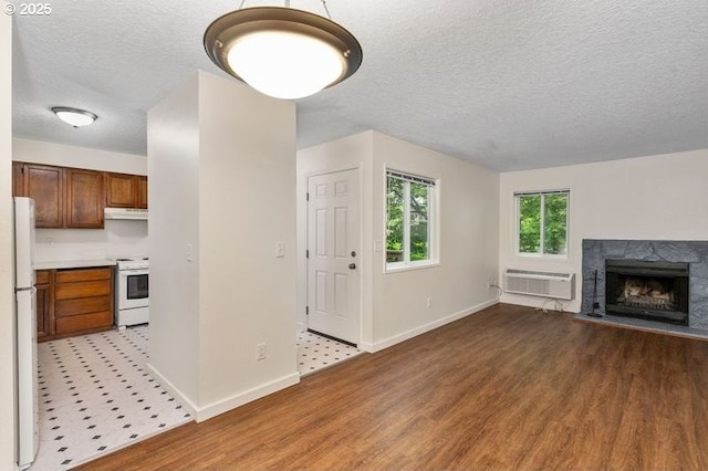 12062 SW Conestoga Dr, Beaverton, OR 97008 - unfurnished living room with an AC wall unit, wood finished floors, a textured ceiling, baseboards, and a premium fireplace