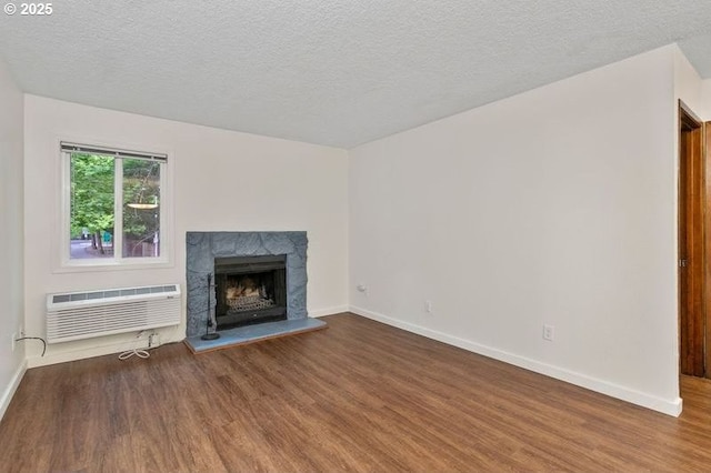 12062 SW Conestoga Dr, Beaverton, OR 97008 - unfurnished living room with wood finished floors, a wall unit AC, baseboards, a premium fireplace, and a textured ceiling