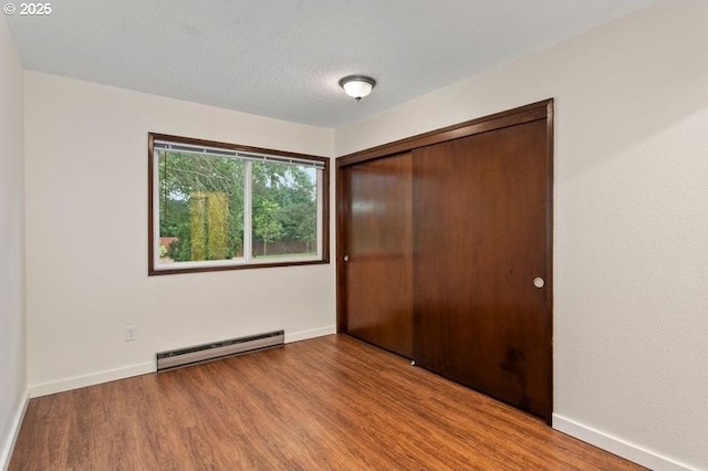12062 SW Conestoga Dr, Beaverton, OR 97008 - unfurnished bedroom with a baseboard heating unit, wood finished floors, a closet, and baseboards