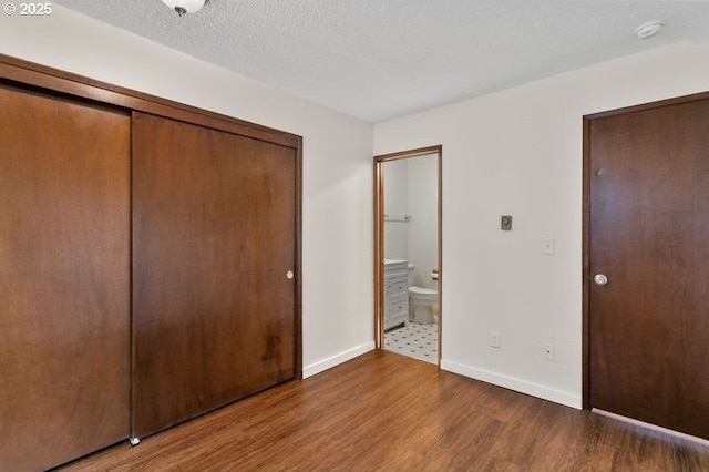 12062 SW Conestoga Dr, Beaverton, OR 97008 - unfurnished bedroom with wood finished floors, a closet, baseboards, and connected bathroom
