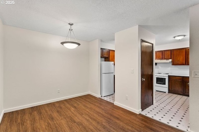12062 SW Conestoga Dr, Beaverton, OR 97008 - kitchen featuring white appliances, under cabinet range hood, wood finished floors, baseboards, and a textured ceiling