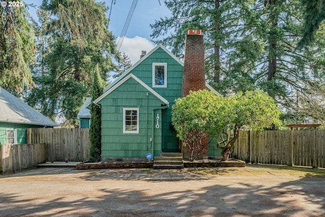 rear view of house with a chimney and fence